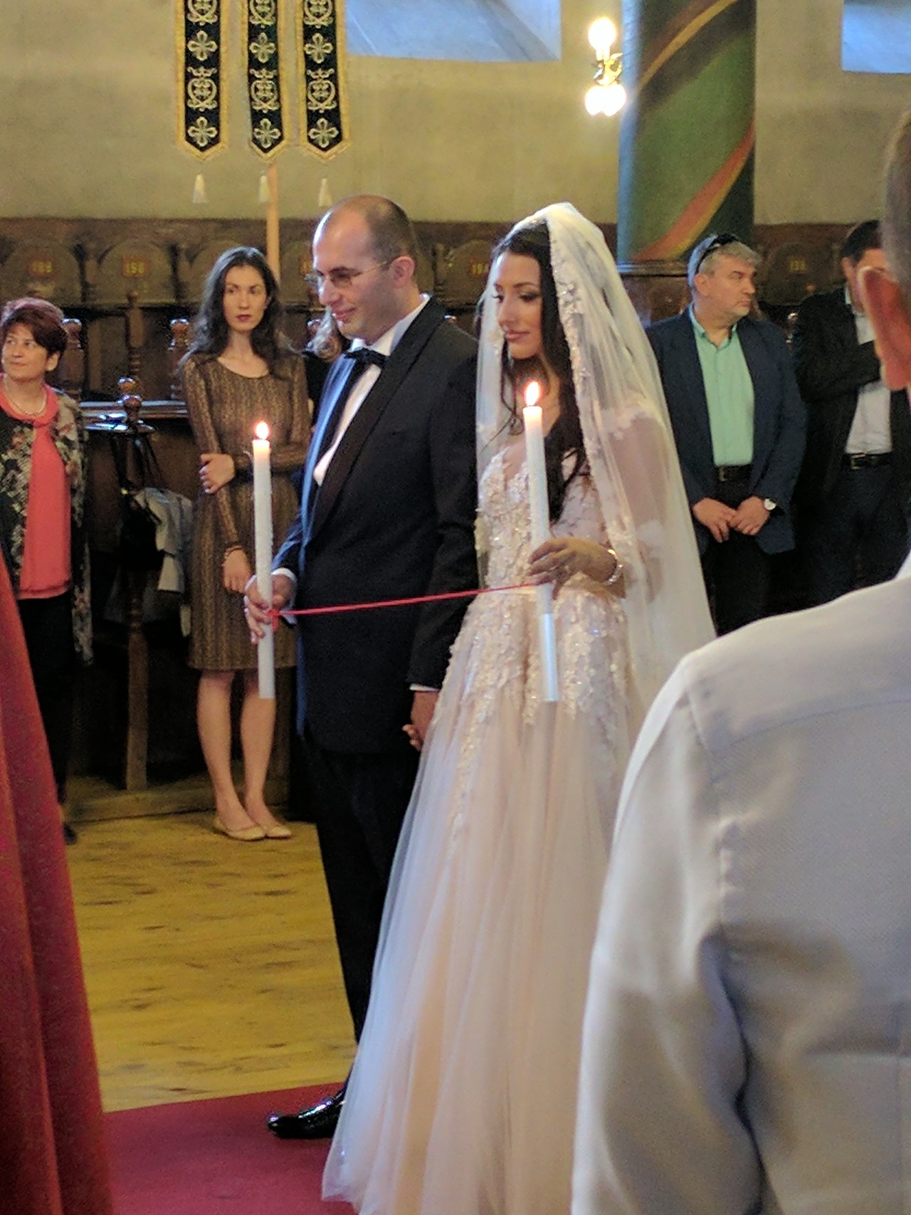 Bride and groom holding candles during a traditional Bulgarian wedding ceremony in a church